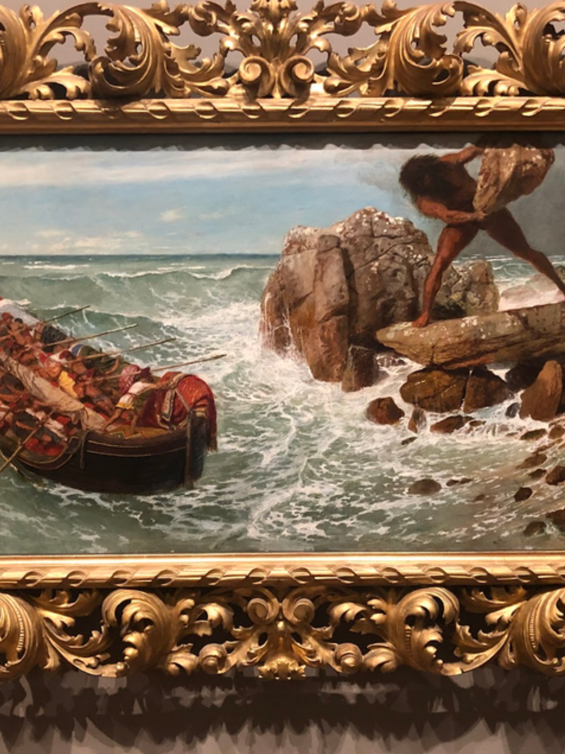 An oil painting at the Museum of Fine Arts Boston depicts the mythological scene of a giant, moving to hurl a stone at a ship full of sailors on a turbulent sea.