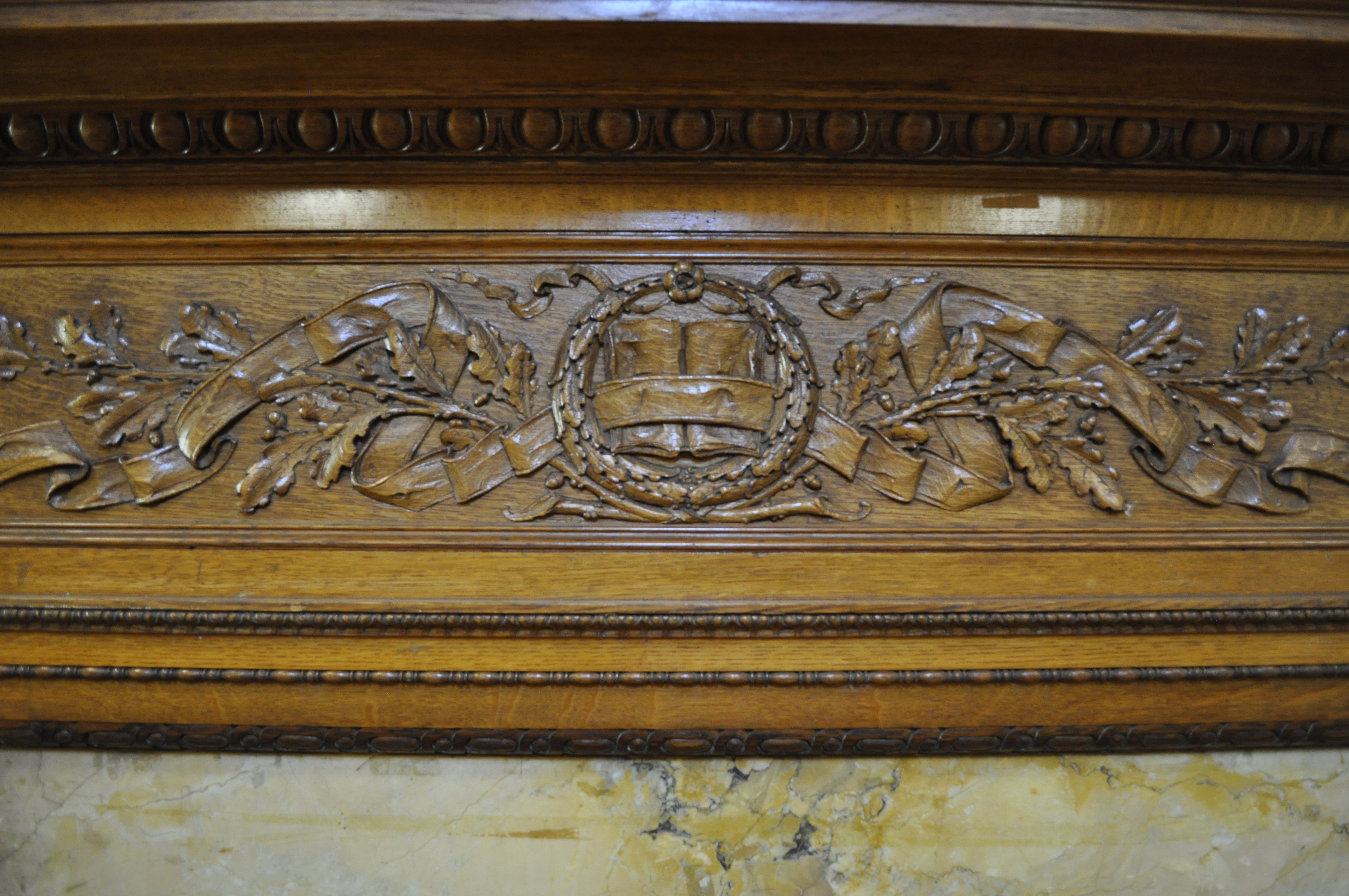 Detail of the decorative woodwork above the fireplace in the Teem Room, depicting an open book among oak leaves.
