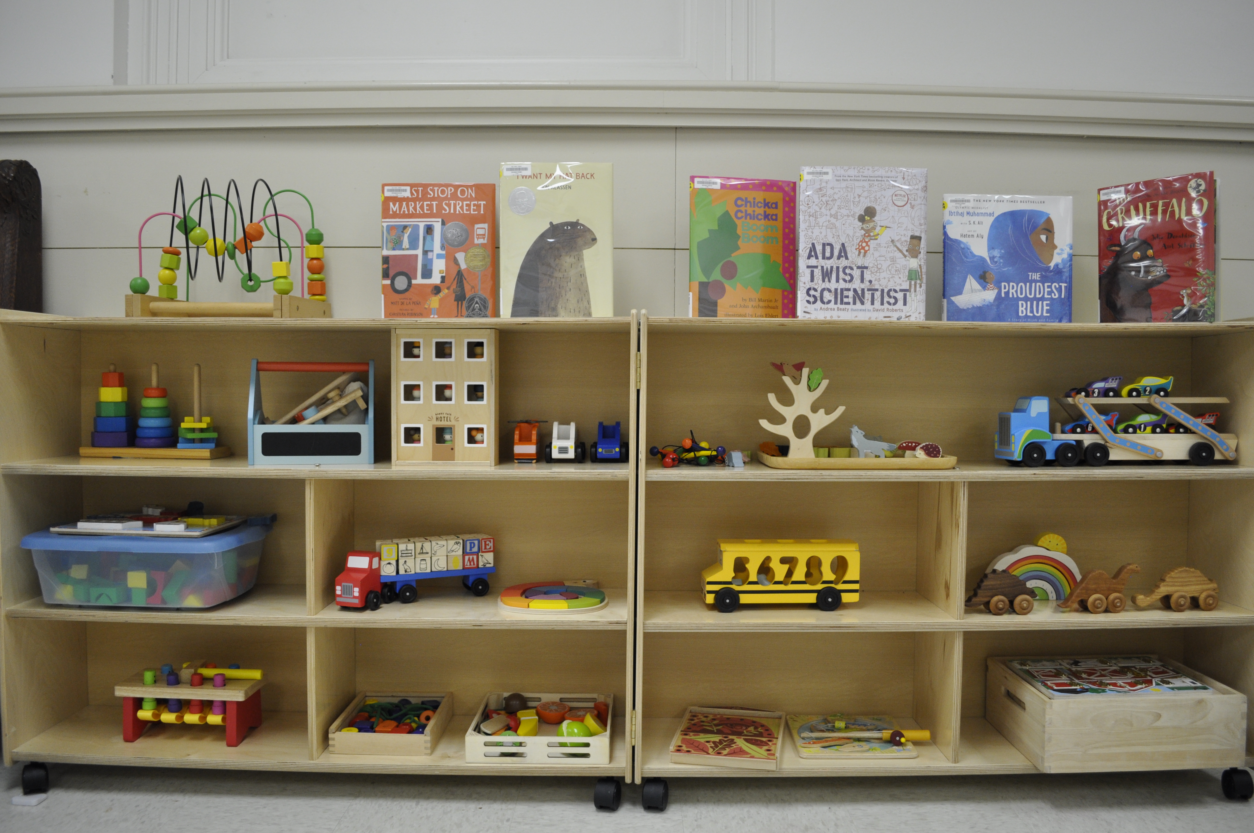 A book shelf with children's picture books and wooden toys.