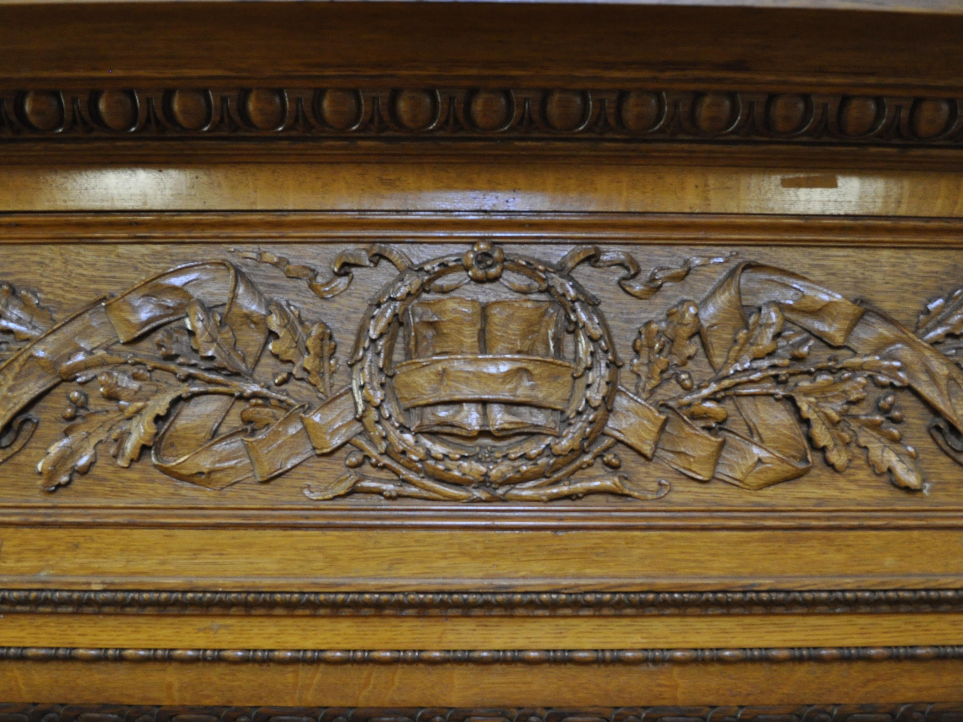 Detail of the decorative woodwork above the fireplace in the Teem Room, depicting an open book among oak leaves.
